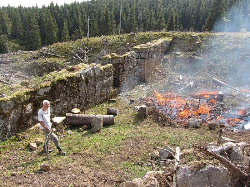 Kanalløypa: Fredrik Zimmer vokter bålet foran damanlegget – sparte oss for mye sleping av kvist og stokker. Her kommer det til å bli et flott sted med utsikt til mye gammel historie. Foto: Lene Li Dragland