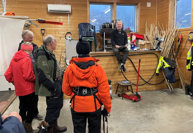 Tore Heldrup Rasmussen deler ut dugnadens arbeidsoppgaver. Denne gangen samlet vi oss inne i Myllagarasjen. Bøtteregn ute – hele dagen. Fantastisk at 46 tøffinger møtte til dugnaden! Foto: Lene Li Dragland