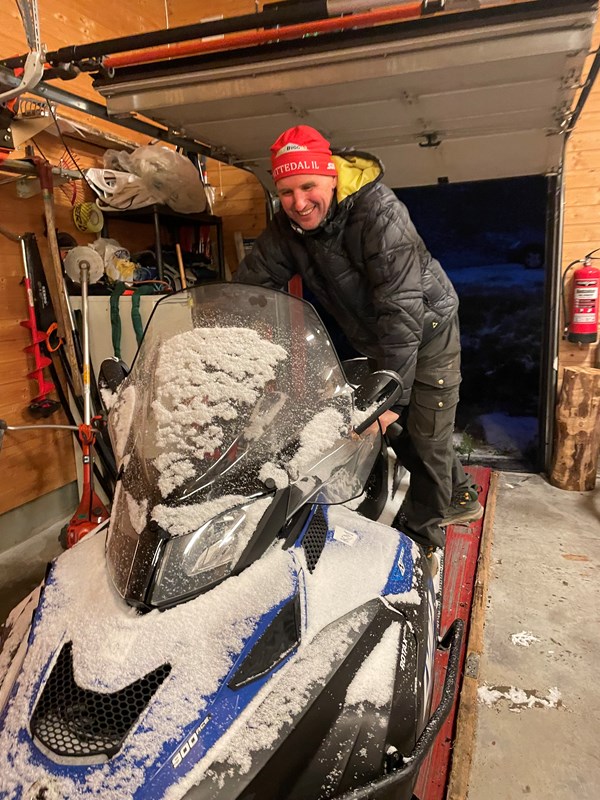 Harald Martinsen kjører snøskuteren tilbake inn i garasjen. I løpet av medlemsmøtet kom den første snøen. Den fine hvite tiden er her. Foto: Nina Grønnestad Heldrup