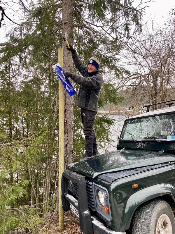 Den bratteste løypa har fått skilt med navnet sitt: Bislingløypa. Leder Tore Heldrup Rasmussen dunker stakene på plass. Foto: Skiltmaker Sverre Sjøblom