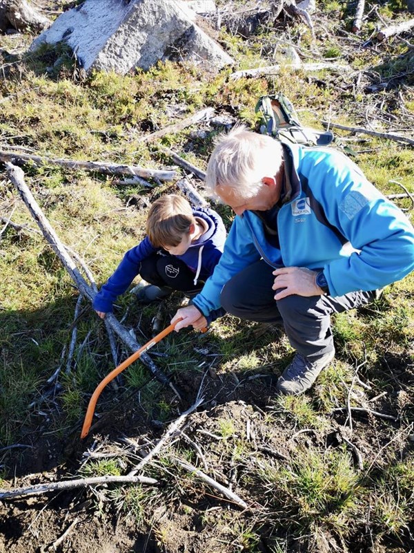 Bestefar Kjell Jacobsen lærer Stellan Loraas å håndtere saga i Rundløypa. Foto: Mette Jacobsen.