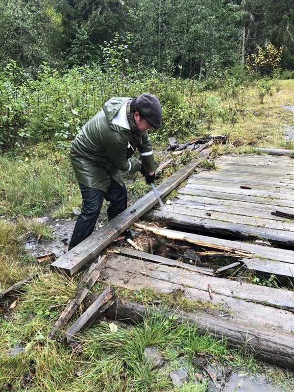 Henrik W. Bärnholdt gyver løs på råtne bord i brua i Vestend. Bak jobber Henrik W. Bärnholdt med brua – mens Lars Petter Fjeld og Eirik Formo er på vei mot neste oppgave. Foto: Heidi Løchen